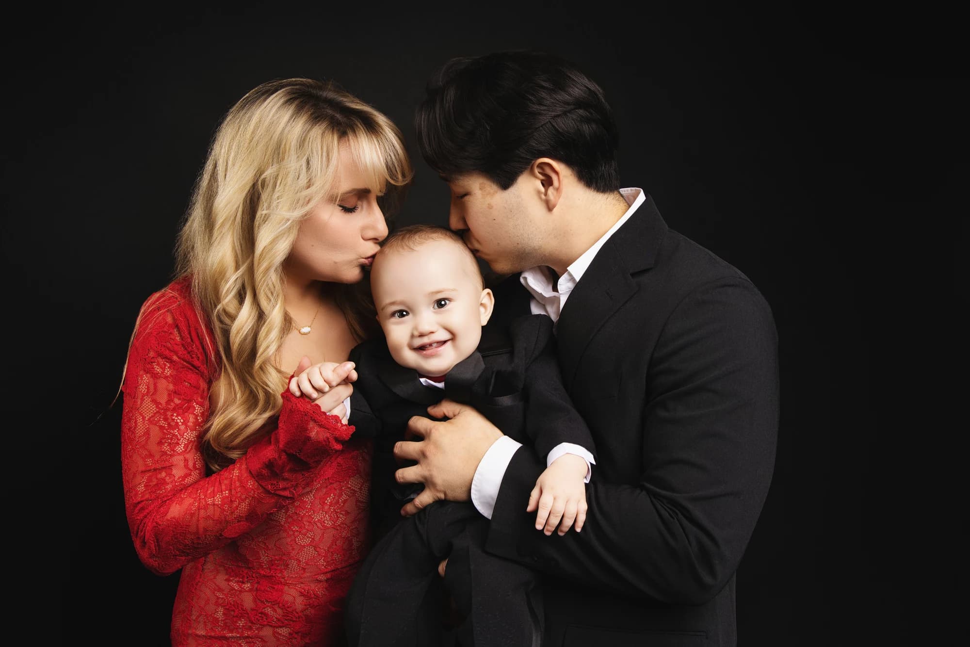Parents leaning in to kiss their smiling young son