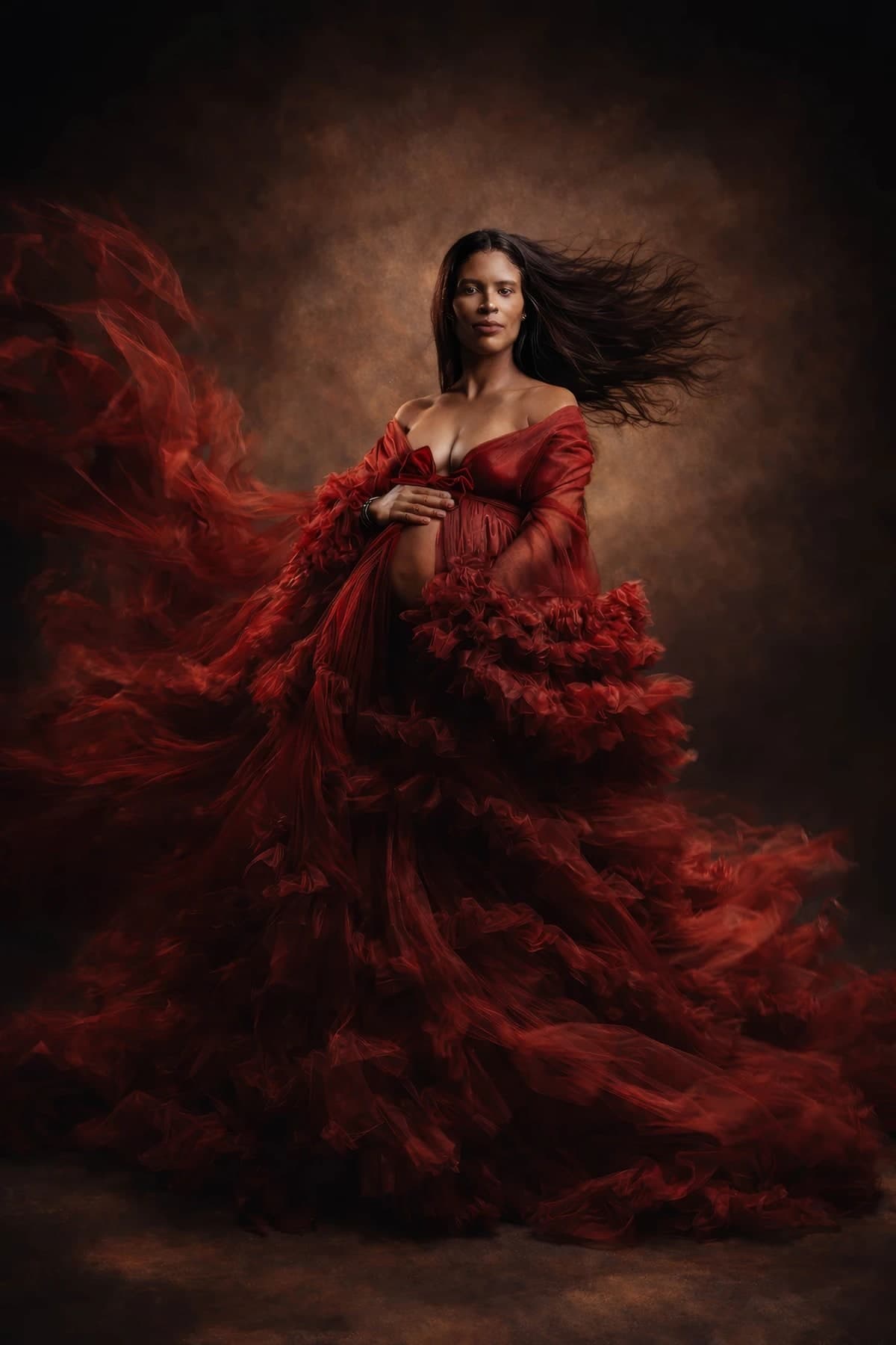 An expectant mother in a flowing red ruffled gown in the studio