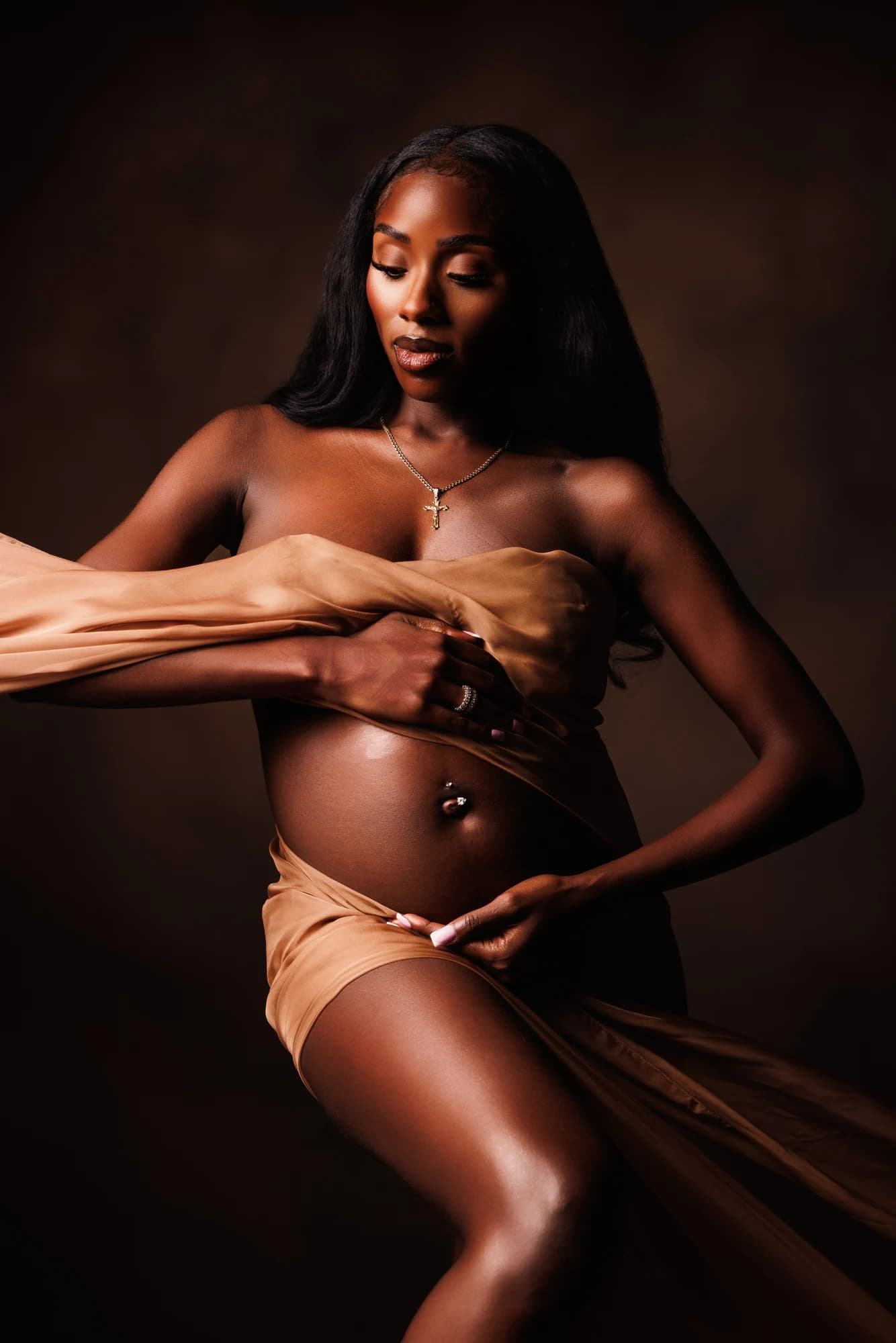 A maternity portrait with flowing copper fabric and dramatic studio lighting