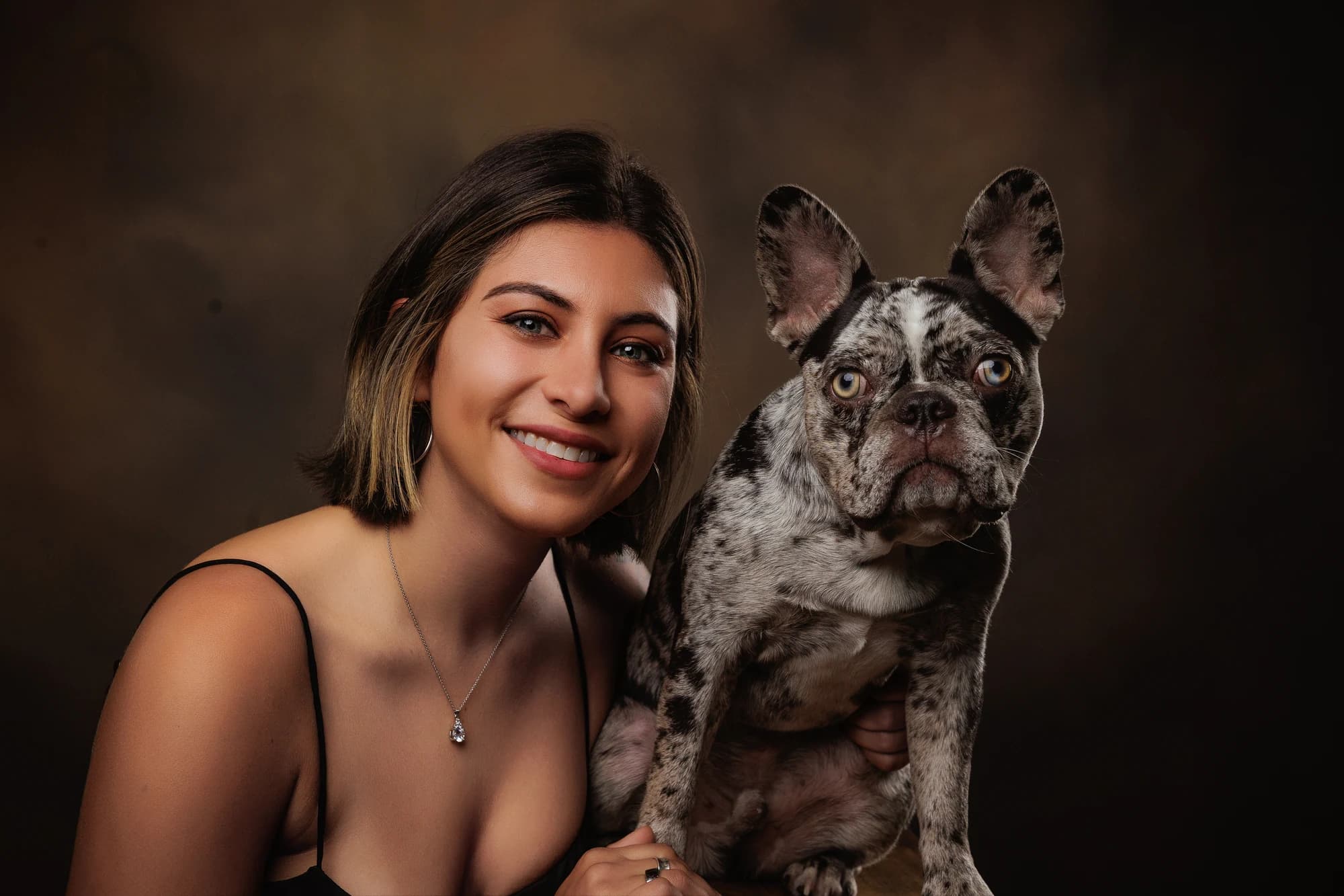 A woman beside her gray merle dog in a close studio portrait